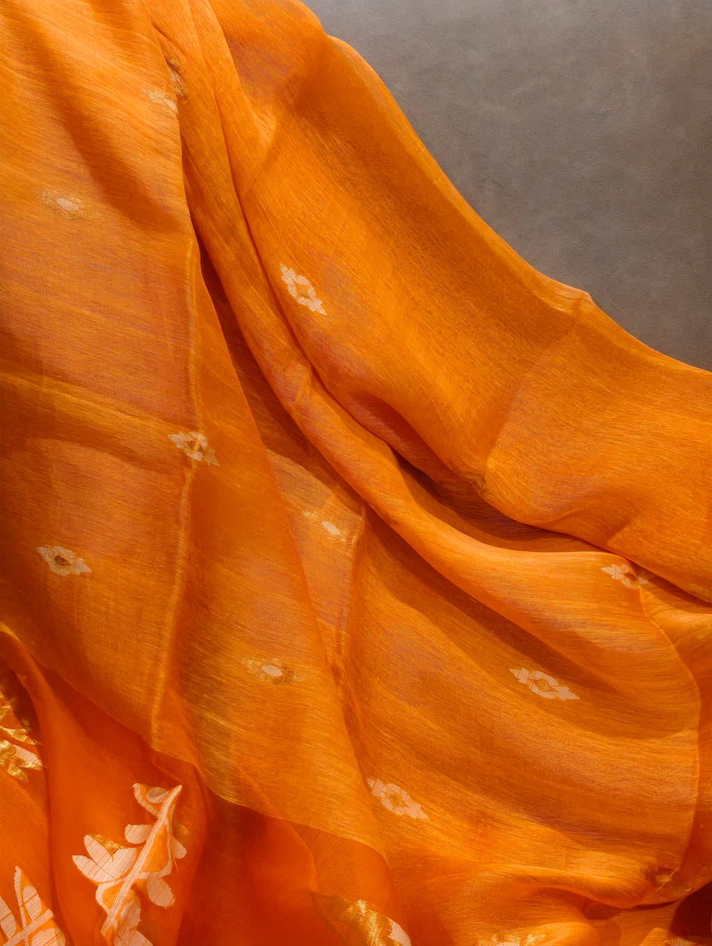 Close-up of orange Matka Muslin Jamdani saree showing handwoven texture and white motifs